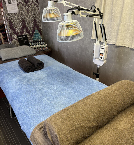 De massagetafel in de praktijkruimte, met de TDP-lampen